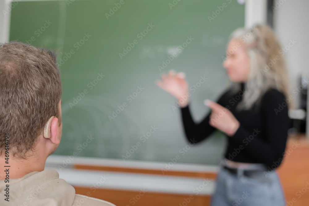 The girl and the guy are talking in Russian sign language. Three deaf students chatting in a university class The girl and the guy are talking in Russian sign language. Three deaf students chatting in a university class