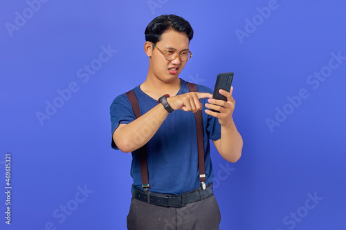 Confused young man on how to use mobile phone to open social media with blank space over purple background