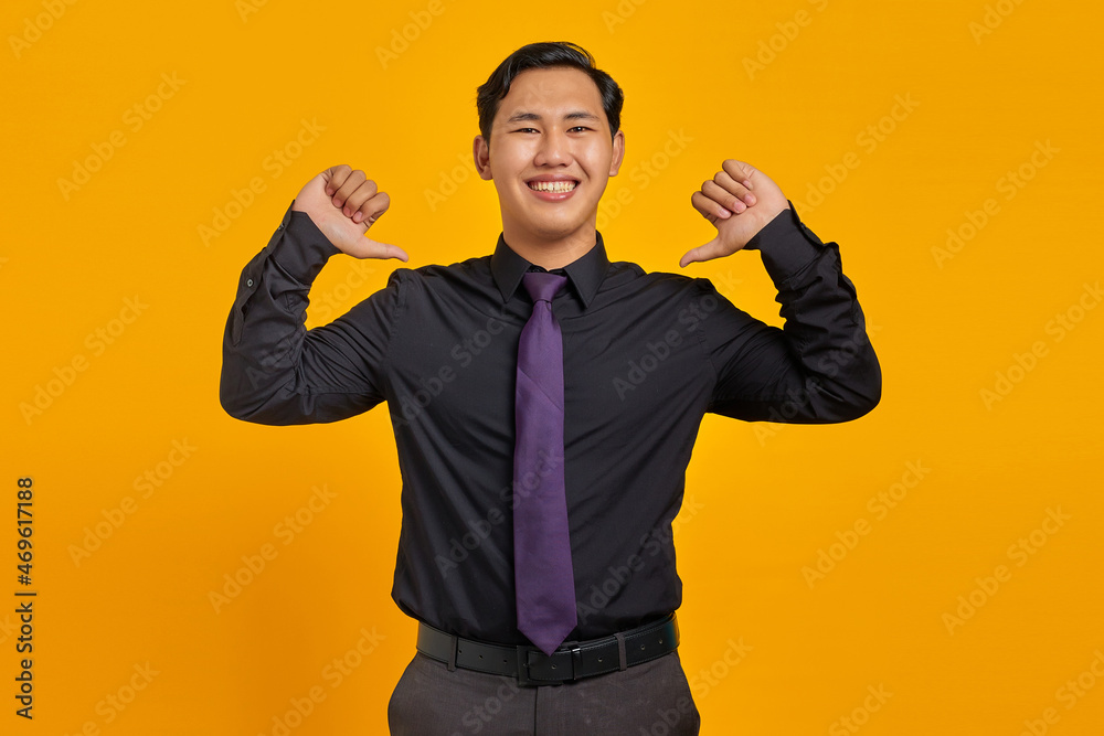 Portrait of smiling young asian businessman pointing at herself with proud on yellow background Portrait of smiling young asian businessman pointing at herself with proud on yellow background