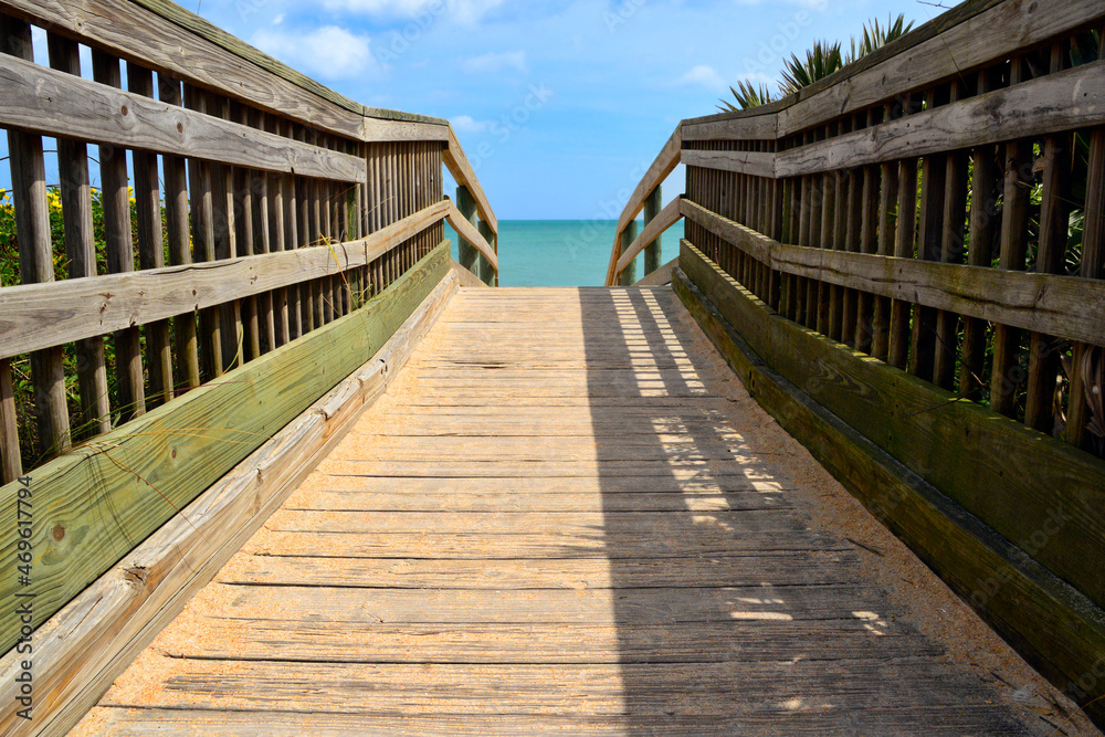 Wooden boardwalk path on an Atlantic Ocean beach over sand dunes on a summer morning Wooden boardwalk path on an Atlantic Ocean beach over sand dunes on a summer morning