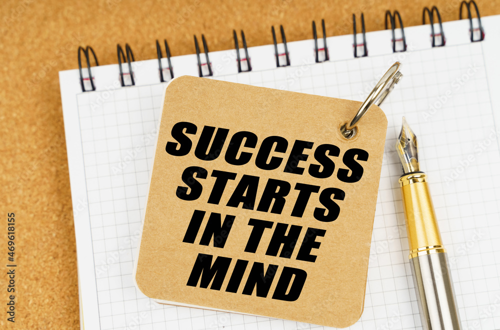There are two notebooks and a pen on the table. On the top notepad, the inscription - Success Starts In The Mind There are two notebooks and a pen on the table. On the top notepad, the inscription - Success Starts In The Mind