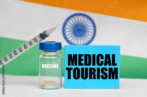 Vaccine, syringe and blue plate with the inscription - MEDICAL TOURISM. In the background the flag of India