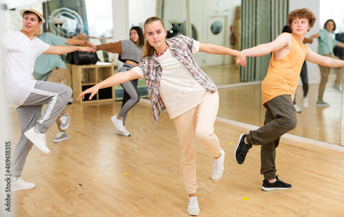 Portrait of teenage girl learning to dance vigorous cheerful lindy hop in pair with boy in choreography class.
