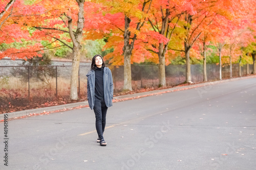 Biracial Asian teen girl enjoying fall autumn leaves along road