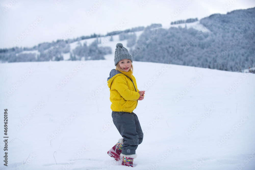 Cute little girl on snow winter nature. Funny kid in winter clothes. Children play outdoors in snow. Kids Christmas vacation.