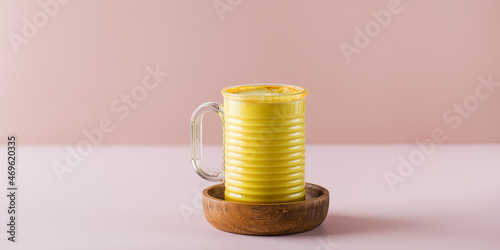 Banner golden latte with turmeric on a pink background. Moon milk for better sleep. Ayurvedic drink. Copy space.