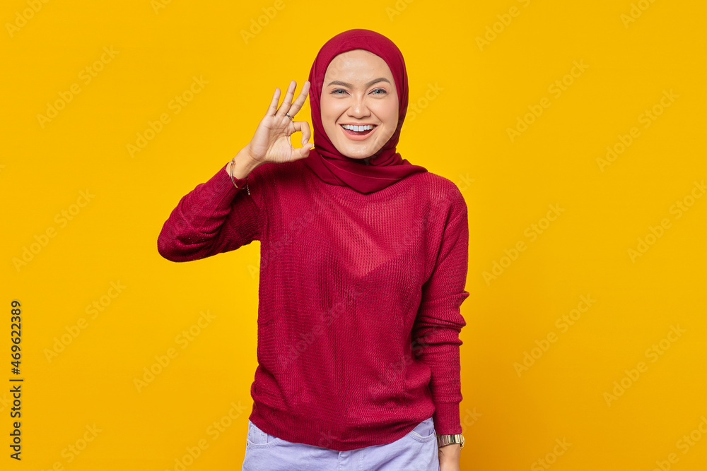 Cheerful beautiful Asian woman showing ok gesture over yellow background Cheerful beautiful Asian woman showing ok gesture over yellow background
