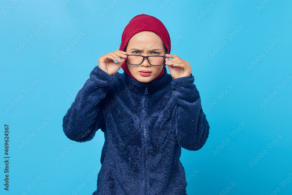 Portrait of shocked young Asian woman wearing glasses with open mouth on blue background Portrait of shocked young Asian woman wearing glasses with open mouth on blue background