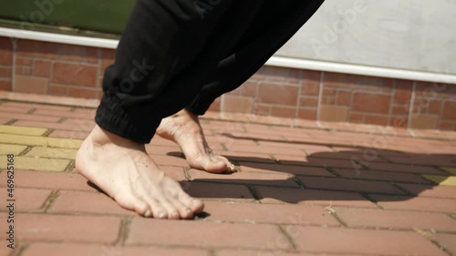 close-up of bare legs on the street on a sunny day. feet trample on the tile, rise on toes.
