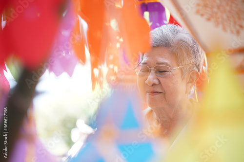 old asian senior woman praying with paper lantern