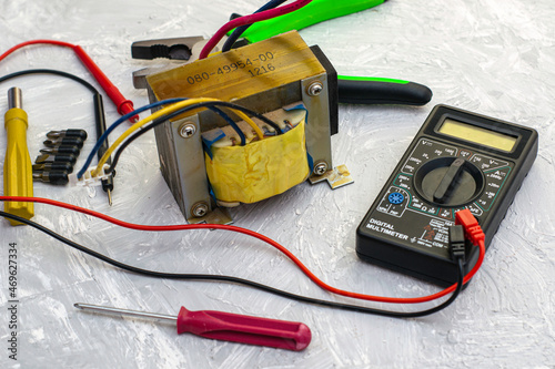 pliers screwdrivers electric transformer and multimeter on the table surface