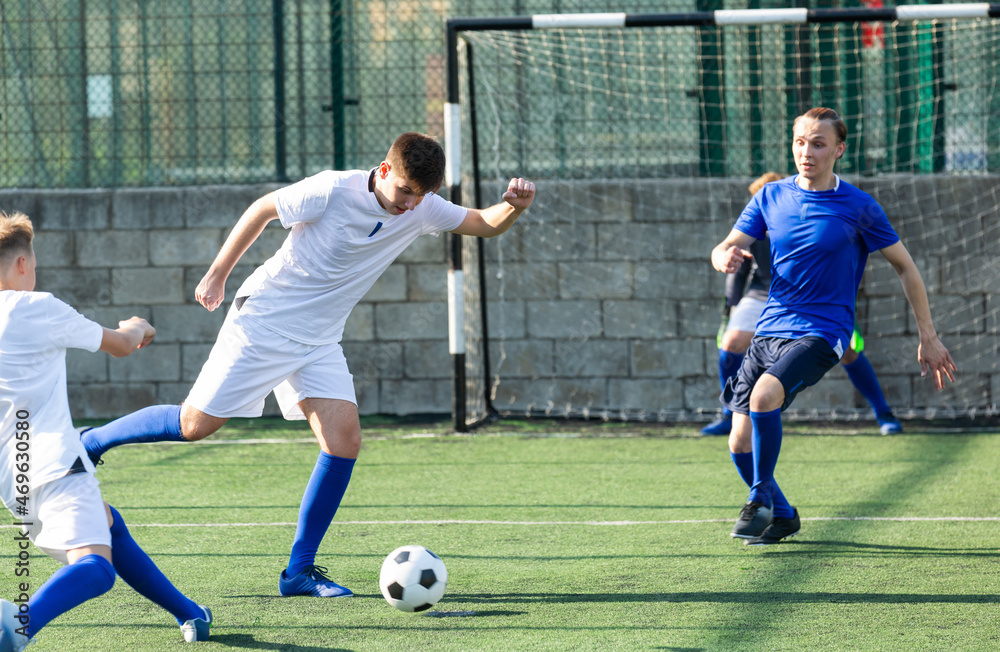 Fototapeta premium Youth football player kicking ball in direction of goal