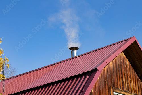 Wallpaper Mural Steel roof of a private house with chimney and smoke against the backdrop of a beautiful blue sky. Torontodigital.ca