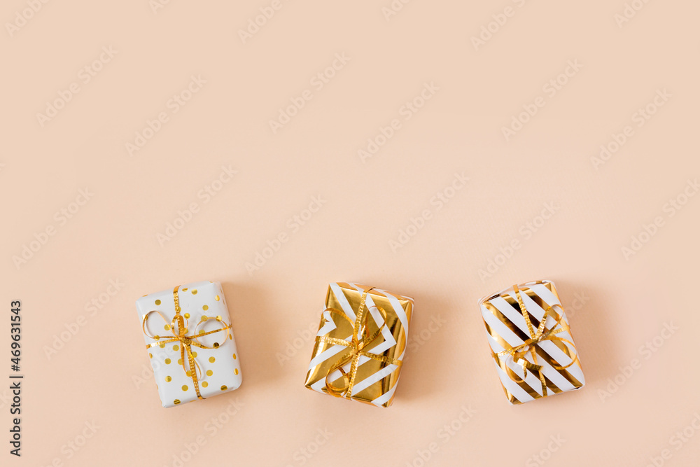 White gift boxes with golden bow isolated on beige pastel background. Christmas and new year shopping and sale. Copy space, frame. Banner. Holiday and celebration concept