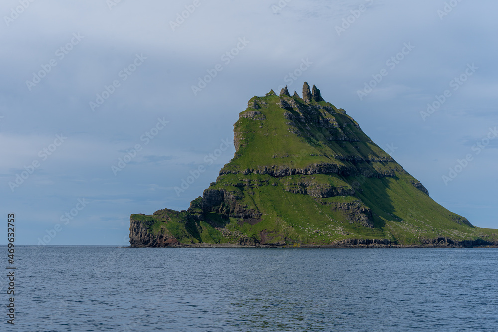 View of the impressive Rocky Drangarnir sea stack and the fishing farms in the Faroe Islands seen from the ferry to Mykines 