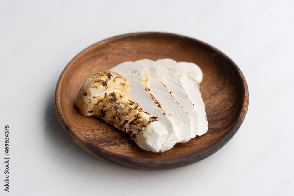 Sliced raw Matsutake mushrooms on a wooden plate isolated on white