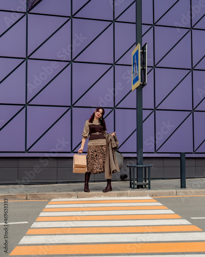 A beautiful girl with shopping bags is walking along a pedestrian crosswalk. Consumerism, shopping, shopping, lifestyle concept © svetograph