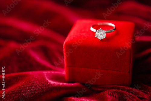 Diamond ring with jewelry gift box on red fabric background © Piman Khrutmuang