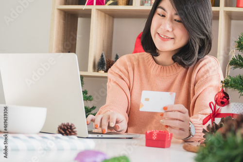 asian young woman using laptop computer and holding credit card for christmas online shopping