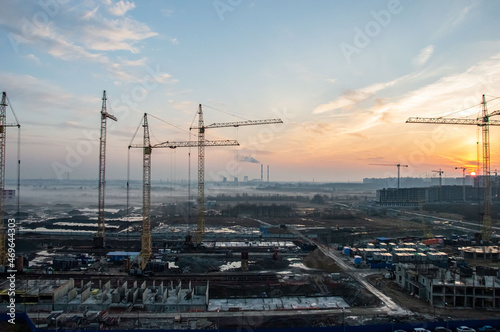 Construction cranes on the background of the sunset.