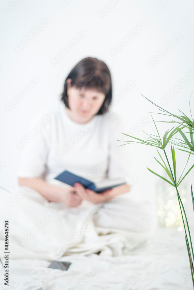 Portrait of young woman with book in hands. Reading before bedtime. Cozy atmosphere, time for yourself. Vertical frame. White background Portrait of young woman with book in hands. Reading before bedtime. Cozy atmosphere, time for yourself. Vertical frame. White background