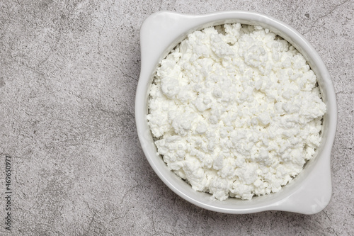 Fresh dairy farm product cottage cheese in ceramic bowl on a concrete background on table close-up top view. Healthy food containing calcium, lactose, protein, methionine, amino acid, vitamin, casein photo
