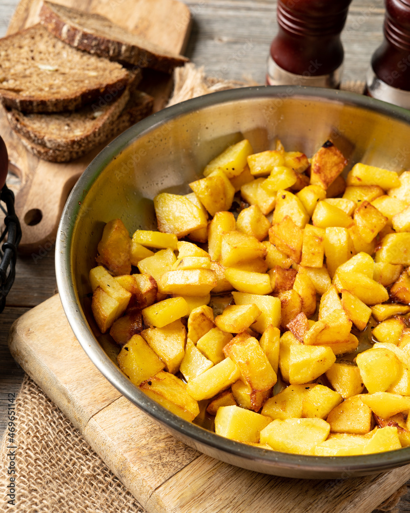 Fried potatoes in a frying pan on a gray wooden table closeup Fried potatoes in a frying pan on a gray wooden table closeup