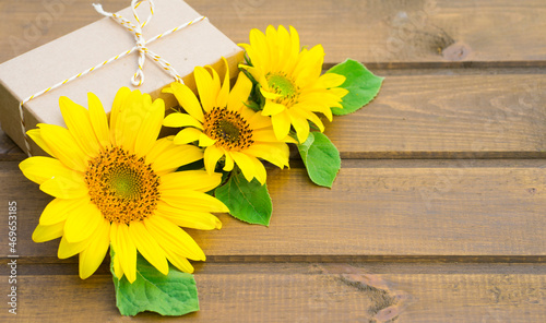 Craft gift box and bright sunflower flowers on wooden background