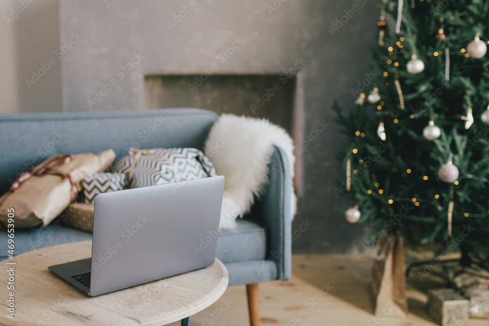 Laptop on table in interior with Christmas tree and presents. Holiday online shopping. Laptop on table in interior with Christmas tree and presents. Holiday online shopping.