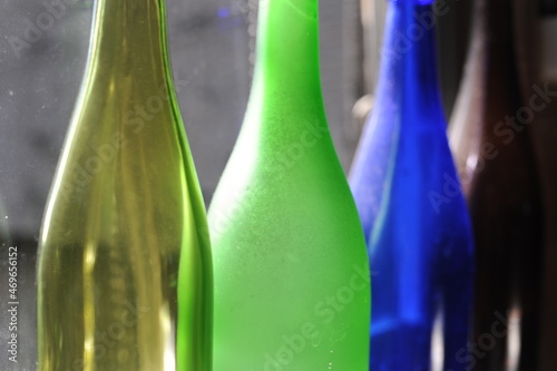 Empty and transparent glass bottles standing in a row, green, blue and brown