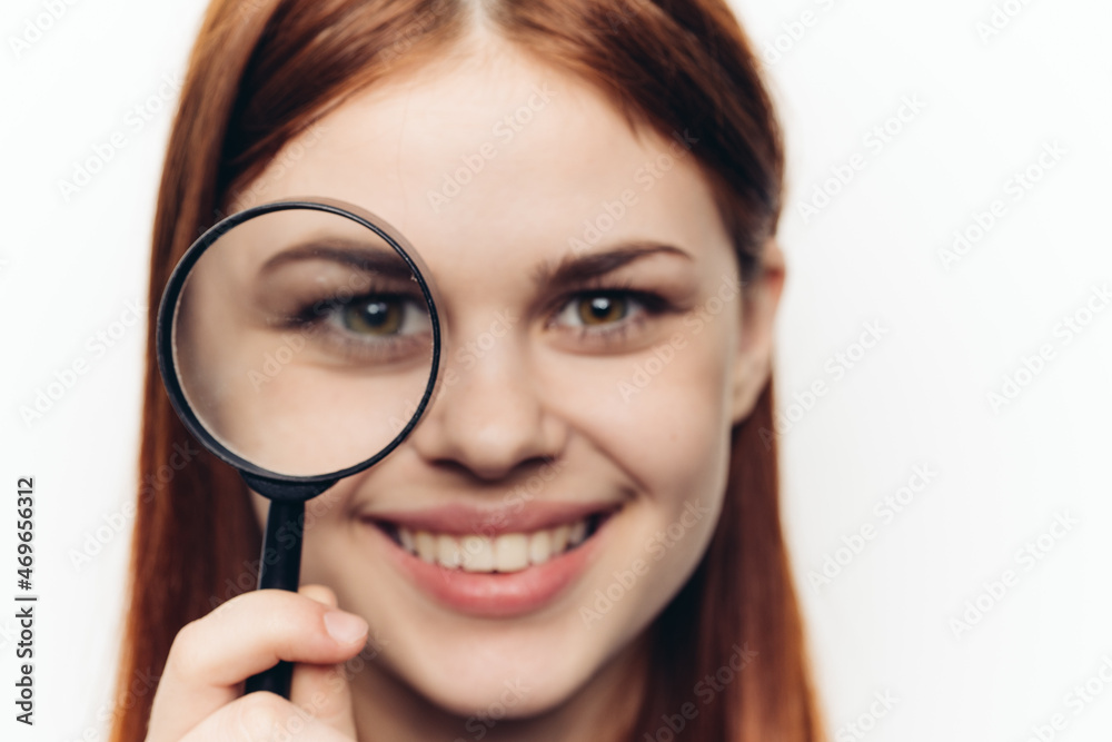 pretty woman grimacing with magnifying glass near face close-up pretty woman grimacing with magnifying glass near face close-up