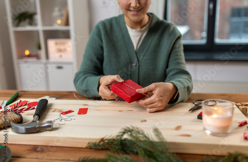 winter holidays and hobby concept - close up of woman with box and rope packing christmas gift or making advent calendar at home