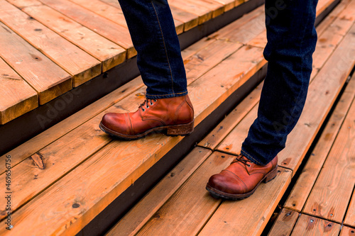 A man stands on a wooden staircase in stylish brown leather shoes. Beautiful men's shoes for your advertising © Anastasia Studio