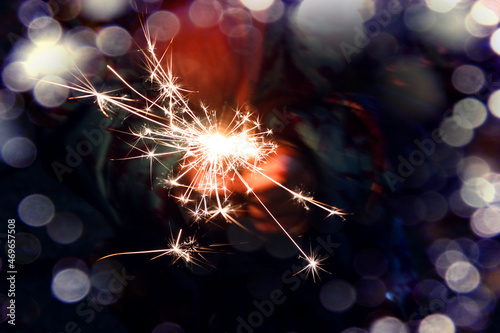 Christmas backgrounds: burning sparklers on the background of hands, close-up, bokeh