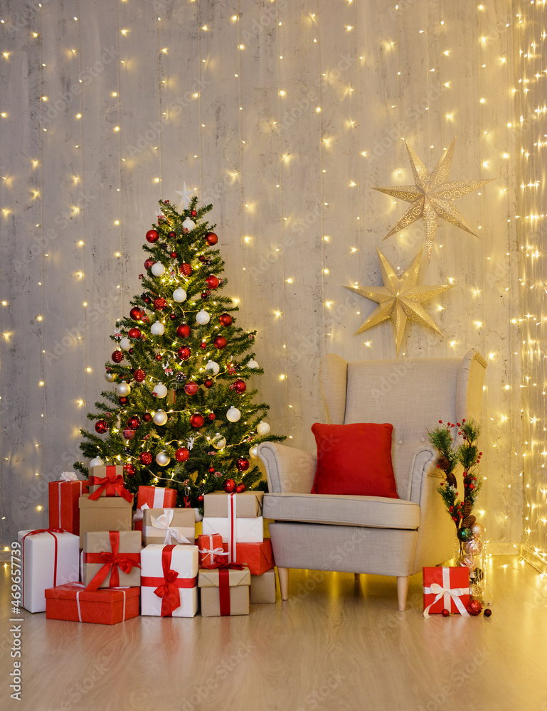 Christmas tree, heap of gift boxes and vintage armchair over grey wall with festive led lights
