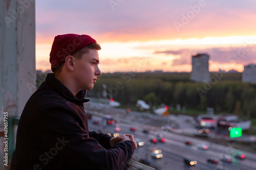 A young man thoughtfully observes the life of the city from the height of the observation deck. Sunset sunlight. the real life of youth.