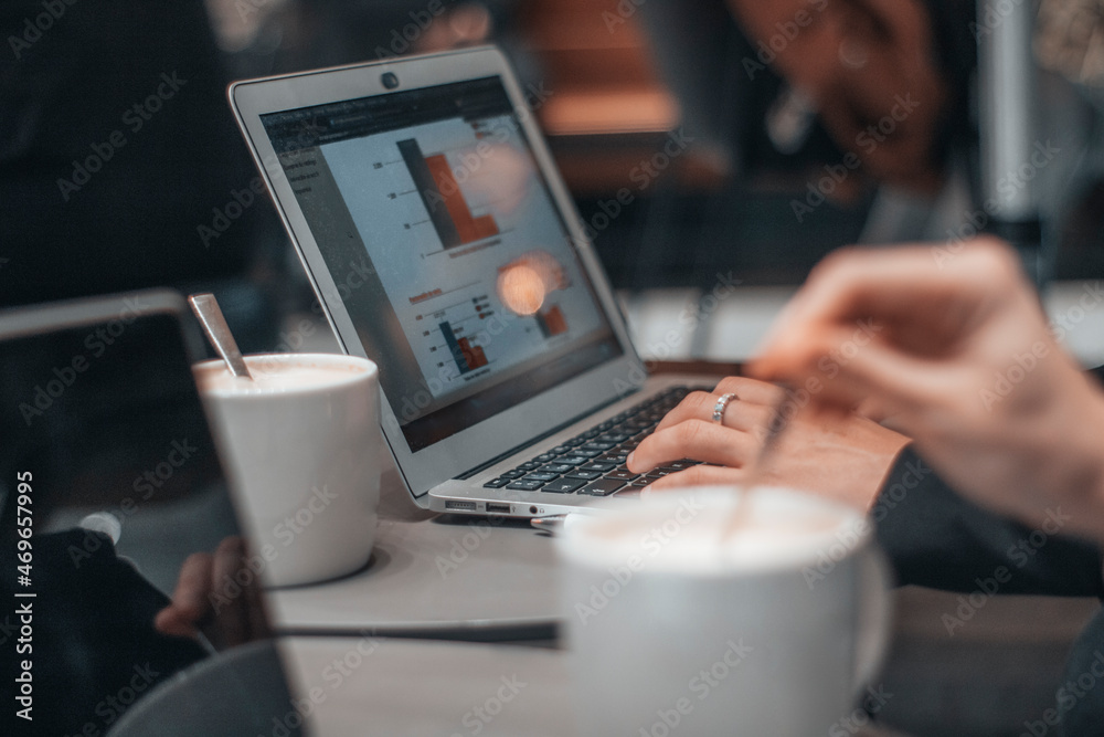 Fototapeta premium Secretaría con seriedad escribiendo ideas y planteamientos en su ordenador laptop en una cafeteria de su ciudad tomando café por la mañana para terminar su trabajo