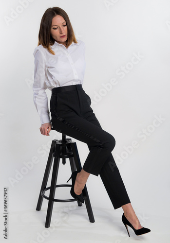 Full length beautiful business woman with blond hair sits on chair and posing on camera isolated on white background, copy space