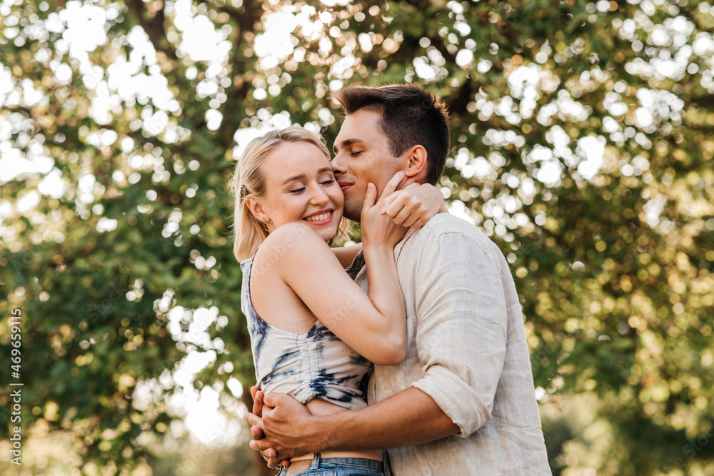 summer holidays, love and people concept - happy young couple kissing and hugging outdoors