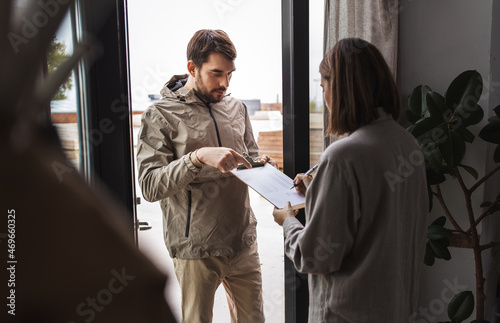 population census, polling and people concept - male social worker asking woman sign papers on clipboard at home photo