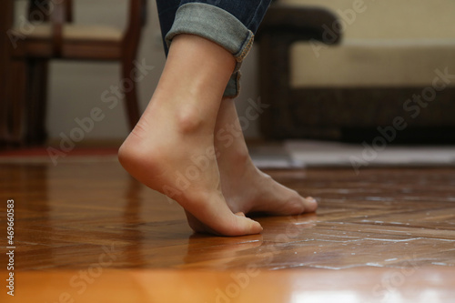 Floor heating. Barefoot woman walking on wooden flooring in modern house. Domestic underfloor heating concept.