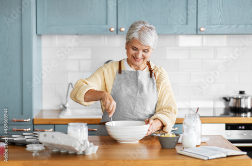 people and culinary concept - happy smiling woman cooking food on kitchen at home