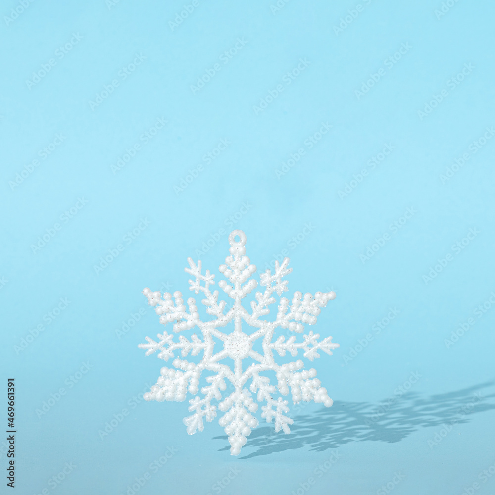 creative Christmas snowflake with sunny shadow against pastel blue background. minimal modern surreal creative idea with copy space.