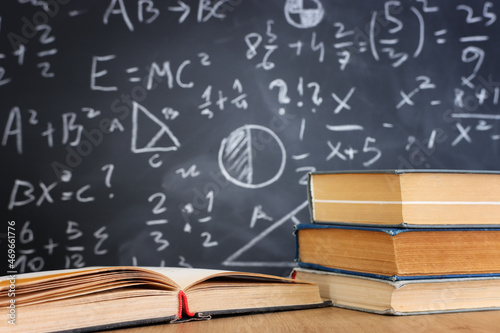 School books on desk infront of blackboard with formulas. education concept