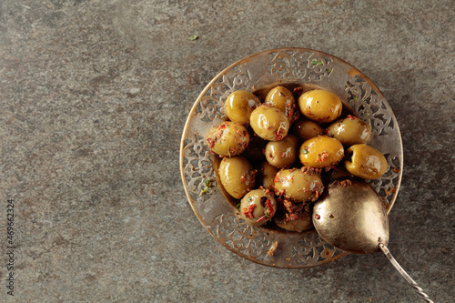 Spicy green olives in olive oil on a old stone table.