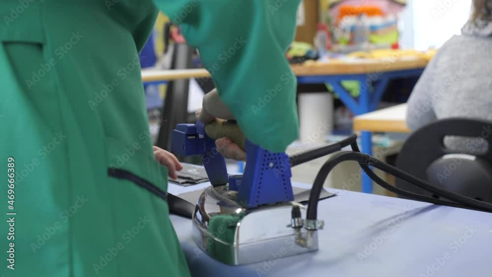 standing woman in green apron ironing textile protection face mask in workshop standing woman in green apron ironing textile protection face mask in workshop