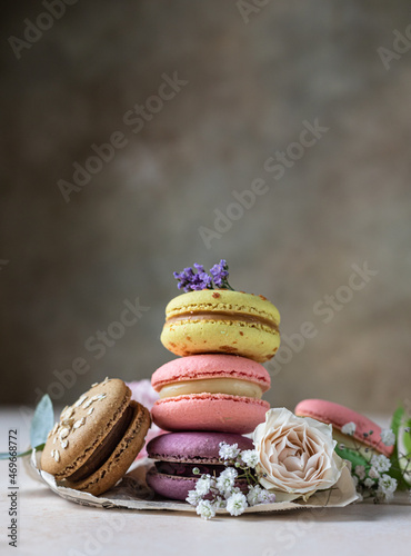 Various types of colorful macarons or macaroons decorated with flowers on light background. Traditional french almond dessert with sweet filling. photo