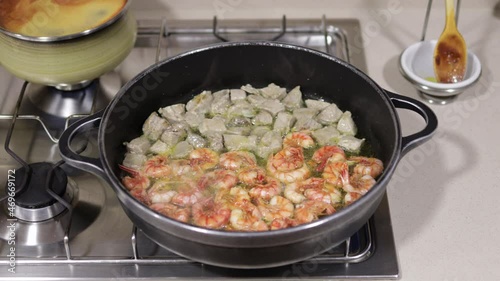 Shrimps and tuna in a frying pan on a gas stove