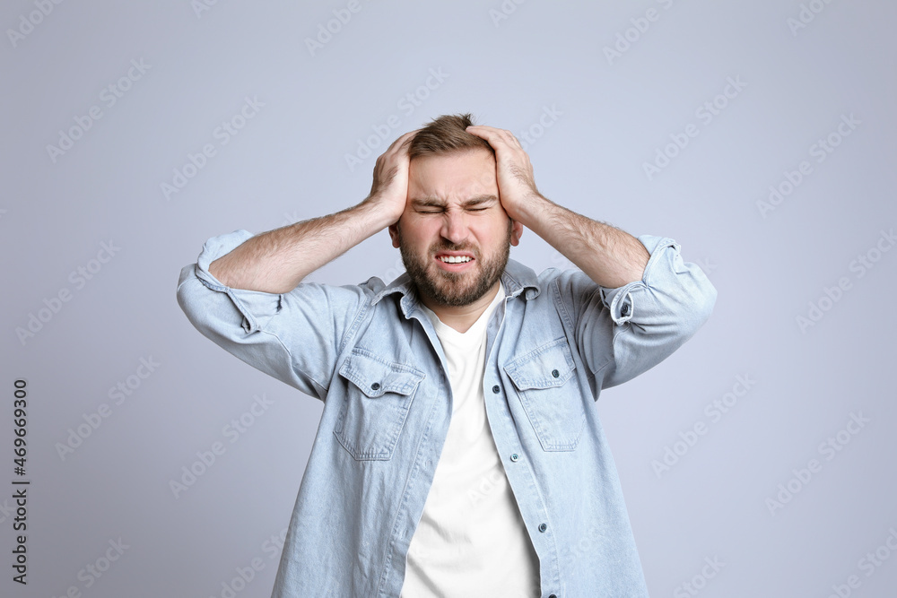 Young man suffering from headache on light background Young man suffering from headache on light background