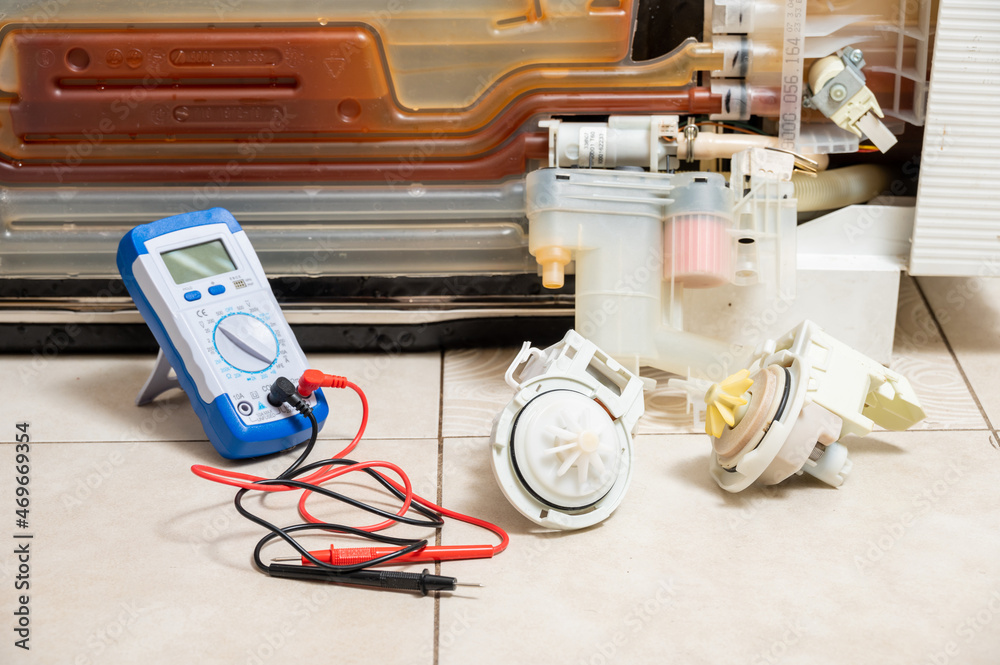 Old and new dishwasher pumps and an electric tester next to the